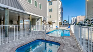 Un edificio residencial con piscina, mobiliario de exterior y una zona de patio cubierta.