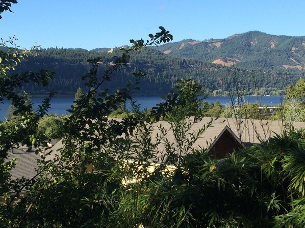 A view of a lake with mountains in the background and a building with a sloped roof in the foreground. - Columbia Tree House - Downtown Hood River with Big View and Fenced Yard (Hood River)
