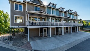 A multi-story residential building with a balcony on the upper floor, a garage, and a driveway. -  Luxury Riverwalk Townhome Overlooking The River, Hot Tub, A/C, Close To Town. (Pagosa Springs)
