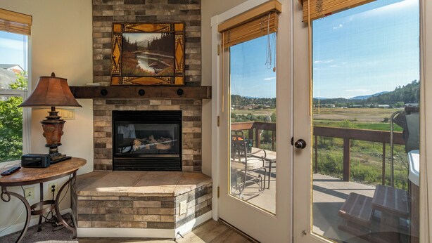 A fireplace with a stone surround, a mounted picture above it, and a table with a lamp to the left. -  Luxury Riverwalk Townhome Overlooking The River, Hot Tub, A/C, Close To Town. (Pagosa Springs)