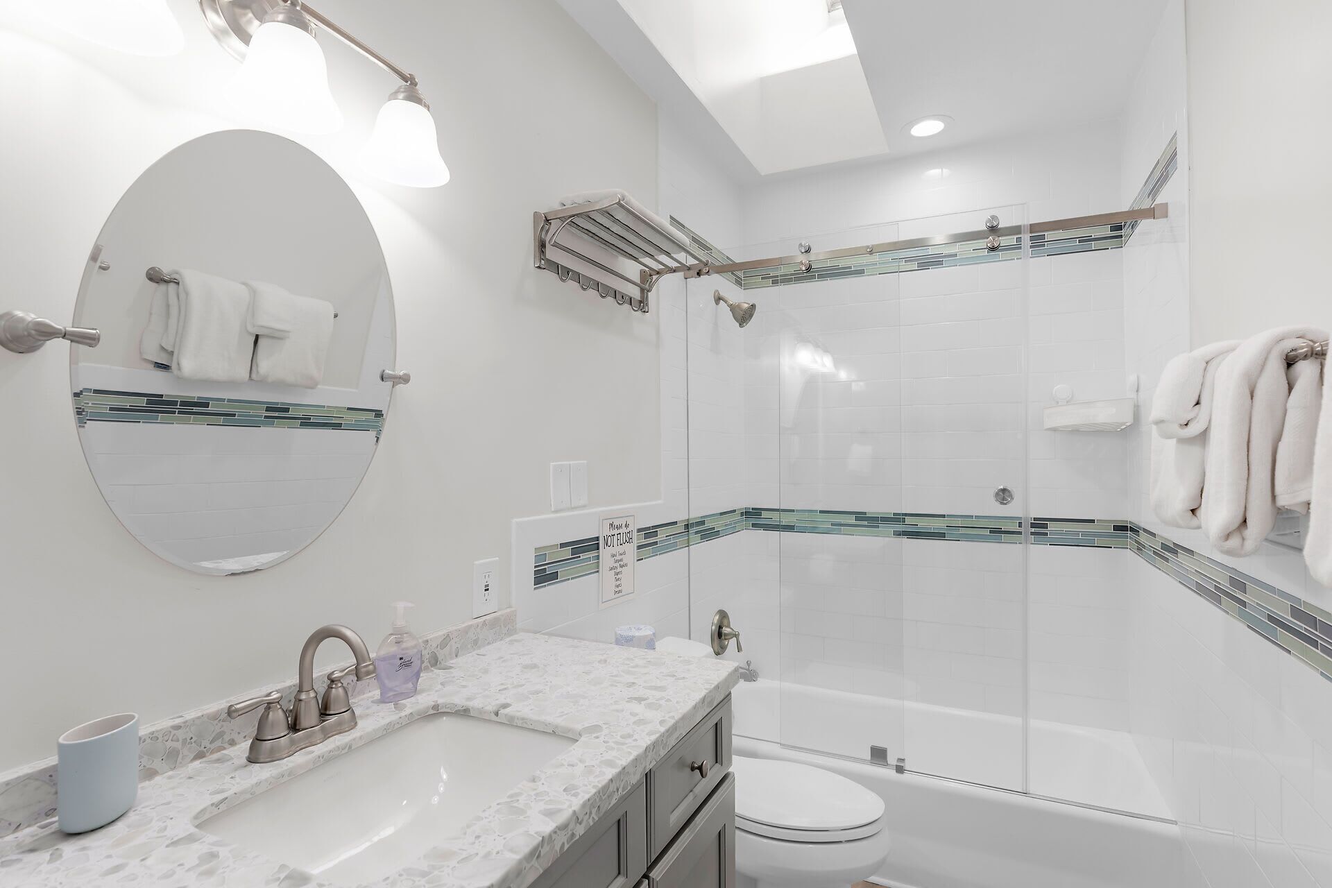 A modern bathroom with a round mirror, a sink, a toilet, and a shower area.