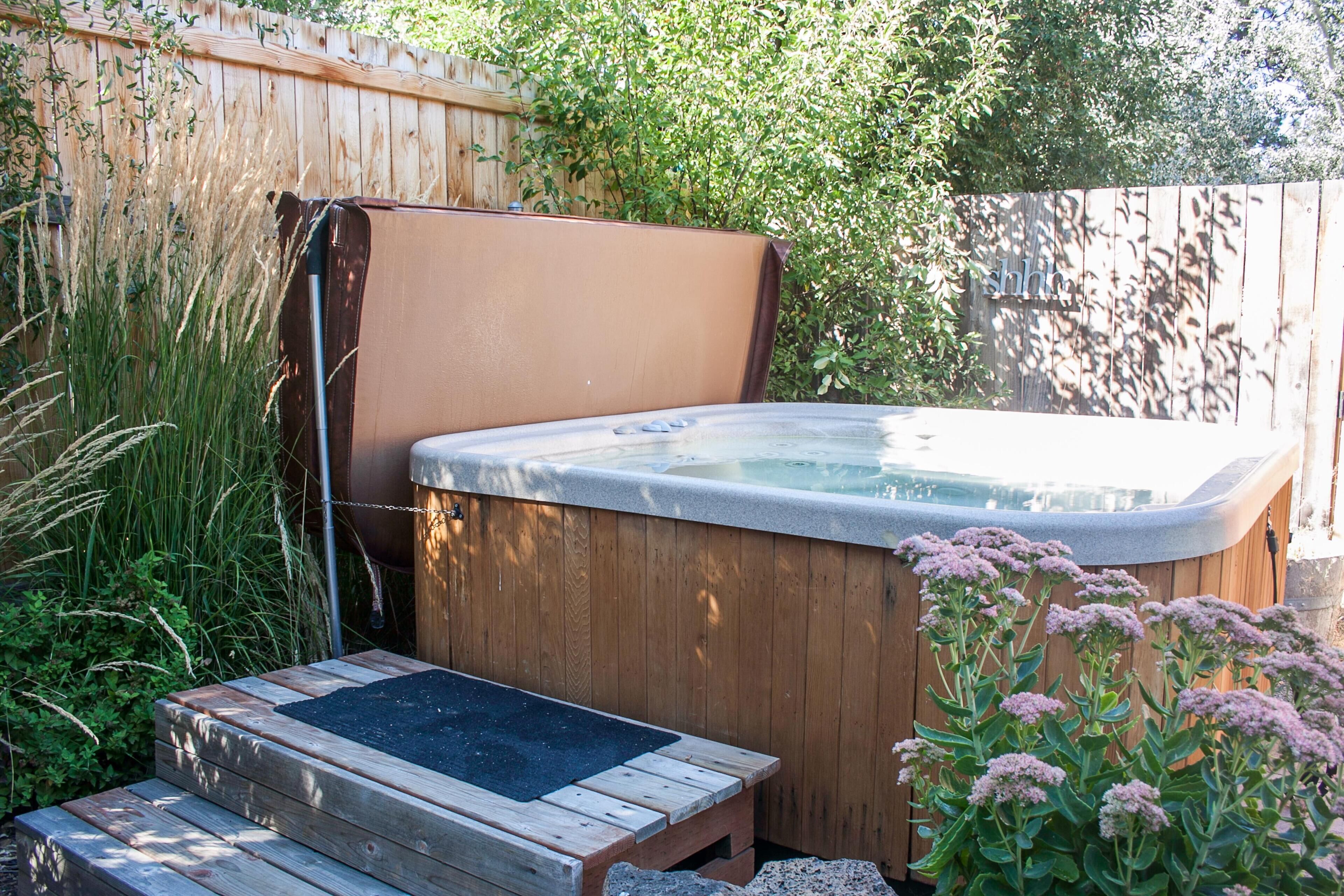 Un bain à remous en bois, avec une terrasse en bois et une clôture en bois en arrière-plan.