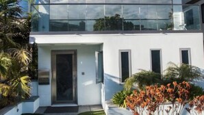 Ein modernes, zweistöckiges Gebäude mit einem Glasbalkon im oberen Geschoss.