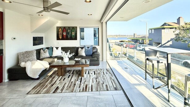 Ein modernes Wohnzimmer mit Sofa, Couchtisch und Kunstwerk. Ein Balkon bietet Blick auf die Stadt.