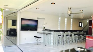 Eine moderne Küche mit einer großen Kochinsel, Barhocker und einem flachbildfernseher an der Wand.