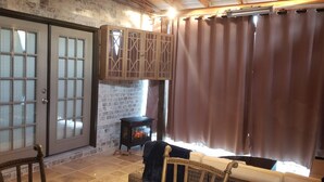 A cozy room with a stone wall, a wooden cabinet, a fireplace, and a large window with curtains. - Uptown Charlotte, Airport, National White Water Center, Other Major Attraction (Charlotte)