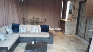 A covered outdoor seating area with a sofa, a coffee table, and a dining table with chairs. - Uptown Charlotte, Airport, National White Water Center, Other Major Attraction (Charlotte)
