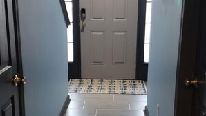 A hallway with a light blue wall, a white door at the end, and a patterned rug on the floor. - Uptown Charlotte, Airport, National White Water Center, Other Major Attraction (Charlotte)