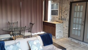 A living room with a sofa, chairs, a dining table, and a kitchen area with a window and a door. - Uptown Charlotte, Airport, National White Water Center, Other Major Attraction (Charlotte)