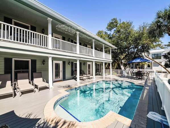 A two-story house with a swimming pool, outdoor furniture, and a covered patio area.