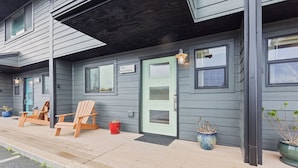 A two-story building with a green door and windows, wooden chairs outside, and potted plants. - Nye Beach, Restaurants, Shop! Walk to the Beach! (Newport)