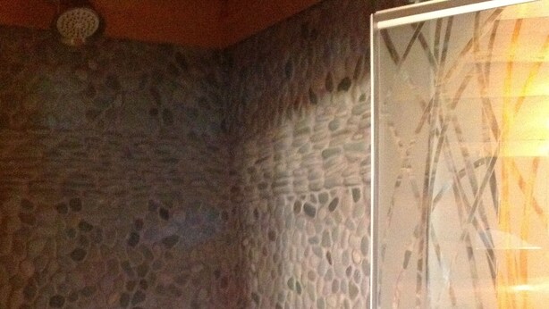 A stone wall with a circular vent and a glass partition with abstract patterns. - Tettegouche Log Cabin Lake Superior views, Sauna, 4 state parks, snowshoe trails (Silver Bay)