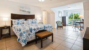 A bedroom with a bed, bedside tables, a ceiling fan, a bench, a chair, and a balcony with a view.