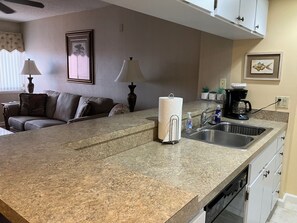 A kitchen with a granite countertop, a coffee maker, a sink, and a dishwasher.