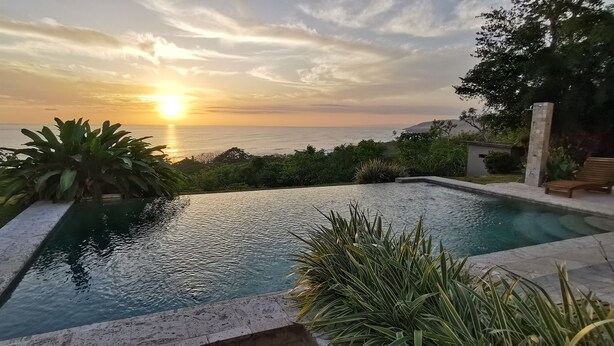 Une piscine offrant une vue sur le coucher de soleil sur l’océan.