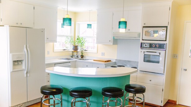 A kitchen with a central island, bar stools, a refrigerator, an oven, and pendant lights. - Spacious and conveniently located duplex (Anchorage)