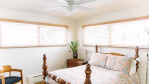 A bedroom with a wooden bed, a chair, a nightstand, a lamp, and a potted plant. - Spacious and conveniently located duplex (Anchorage)