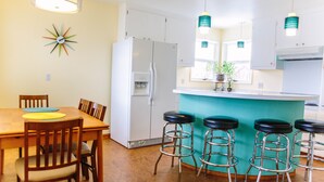 A kitchen with a white refrigerator, wooden chairs, a bar stool area, and pendant lights. - Spacious and conveniently located duplex (Anchorage)