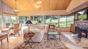 A spacious living room with a high ceiling, large windows, a fireplace, and comfortable seating. - Come take in the ocean, gaze at the starry skies, commune with nature. (The Sea Ranch)