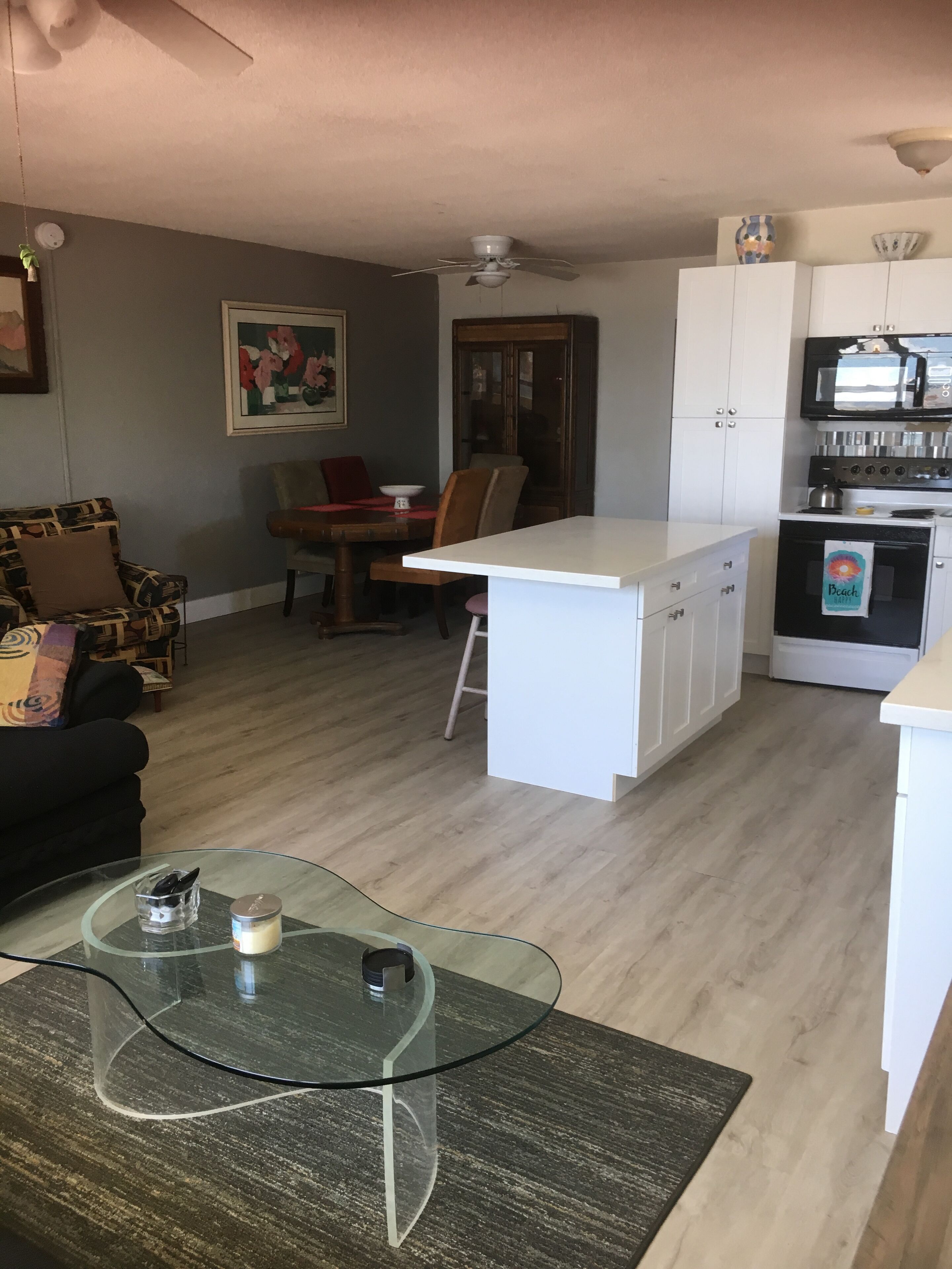 Un espacio habitable compacto con comedor, kitchenette y una mesa de centro de vidrio.