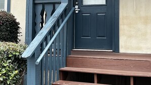A front door with the number 101, a wooden staircase, and a bench outside a building with a beige exterior. - Luxury Condo In Town (Helen)