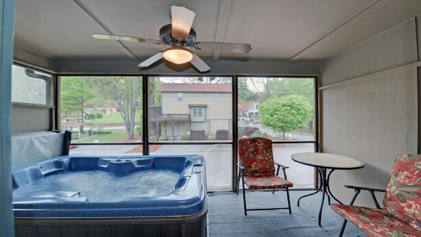 A room with a hot tub, a ceiling fan, a chair, and a table. - Luxury Condo In Town (Helen)