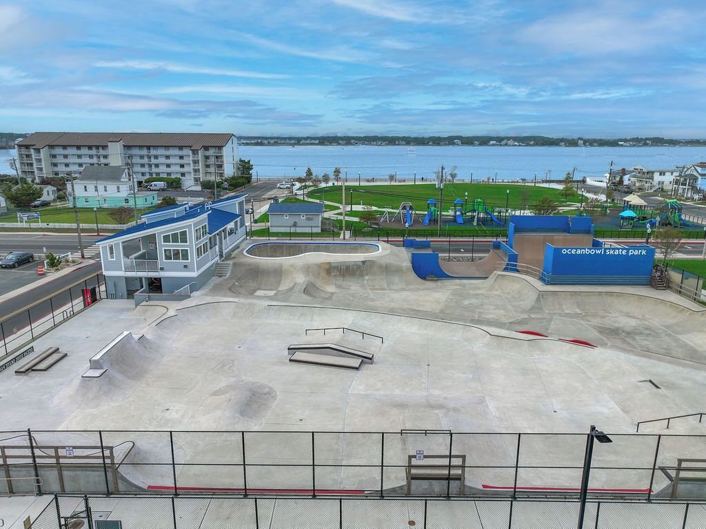 A skate park with ramps and a building in the background.