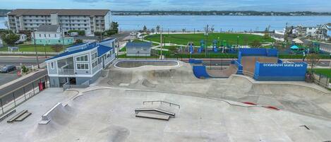 A skate park with ramps and a building in the background.