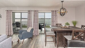 Ein Essbereich mit Holztisch und Stühlen, einer Chandeliebre und Blick durch große Glastüren nach draußen.