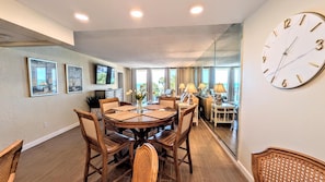 A dining area with a round table, chairs, and a wall-mounted clock.