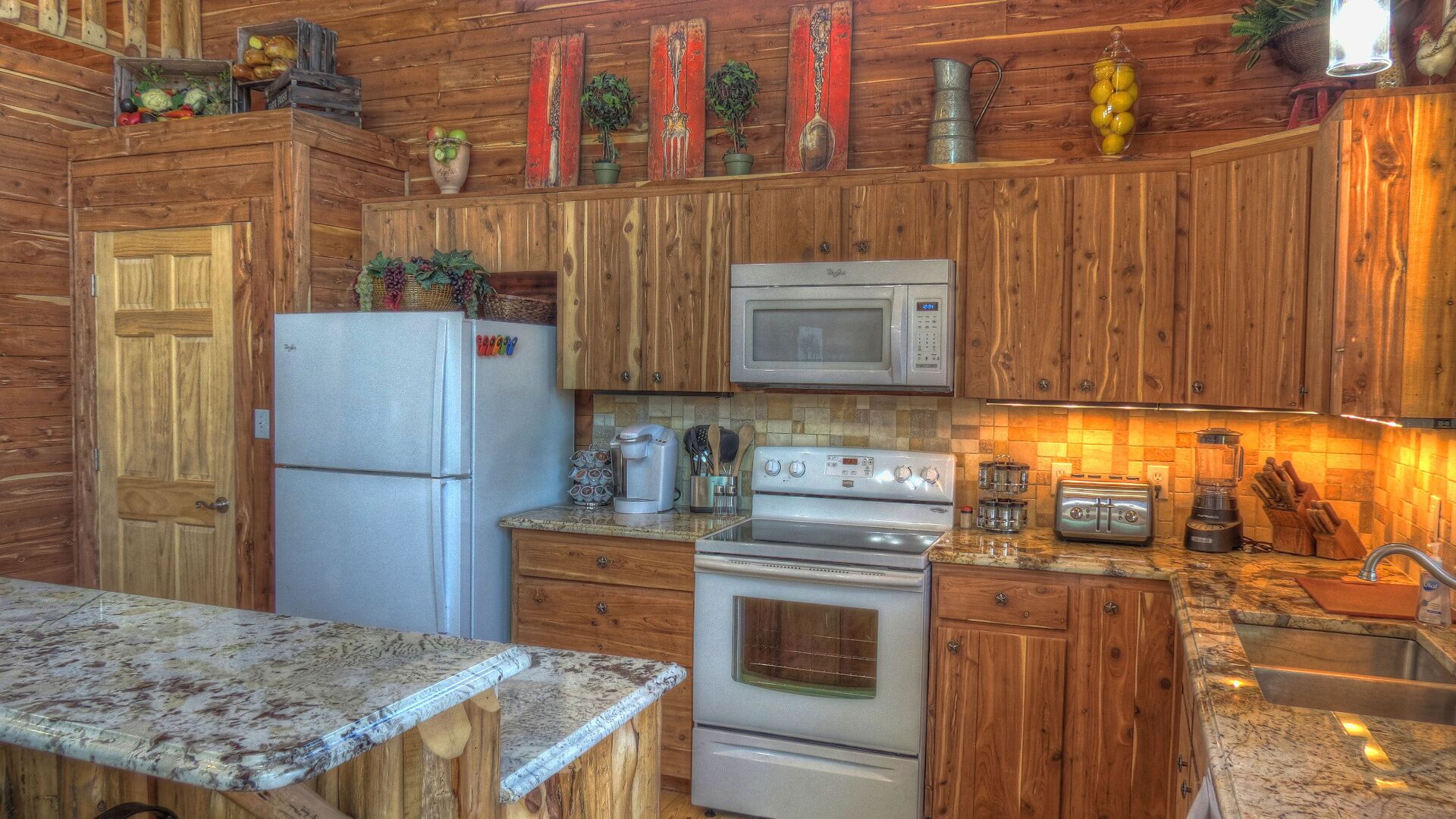 Une cuisine avec des meubles de rangement en bois, un réfrigérateur, un four à micro-ondes, un four traditionnel et un évier.