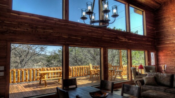 Una cabaña de madera con ventanas amplias, una terraza y un rincón de descanso acogedor.