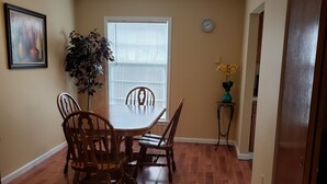 A dining area with a wooden table and chairs, a potted plant, and a clock on the wall. - Cozy and Spacious Lexington stay (Lexington)