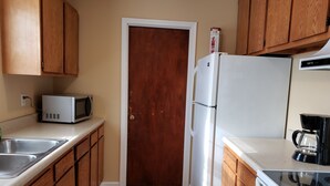 A kitchen with wooden cabinets, a white refrigerator, a microwave, and a coffee maker. - Cozy and Spacious Lexington stay (Lexington)