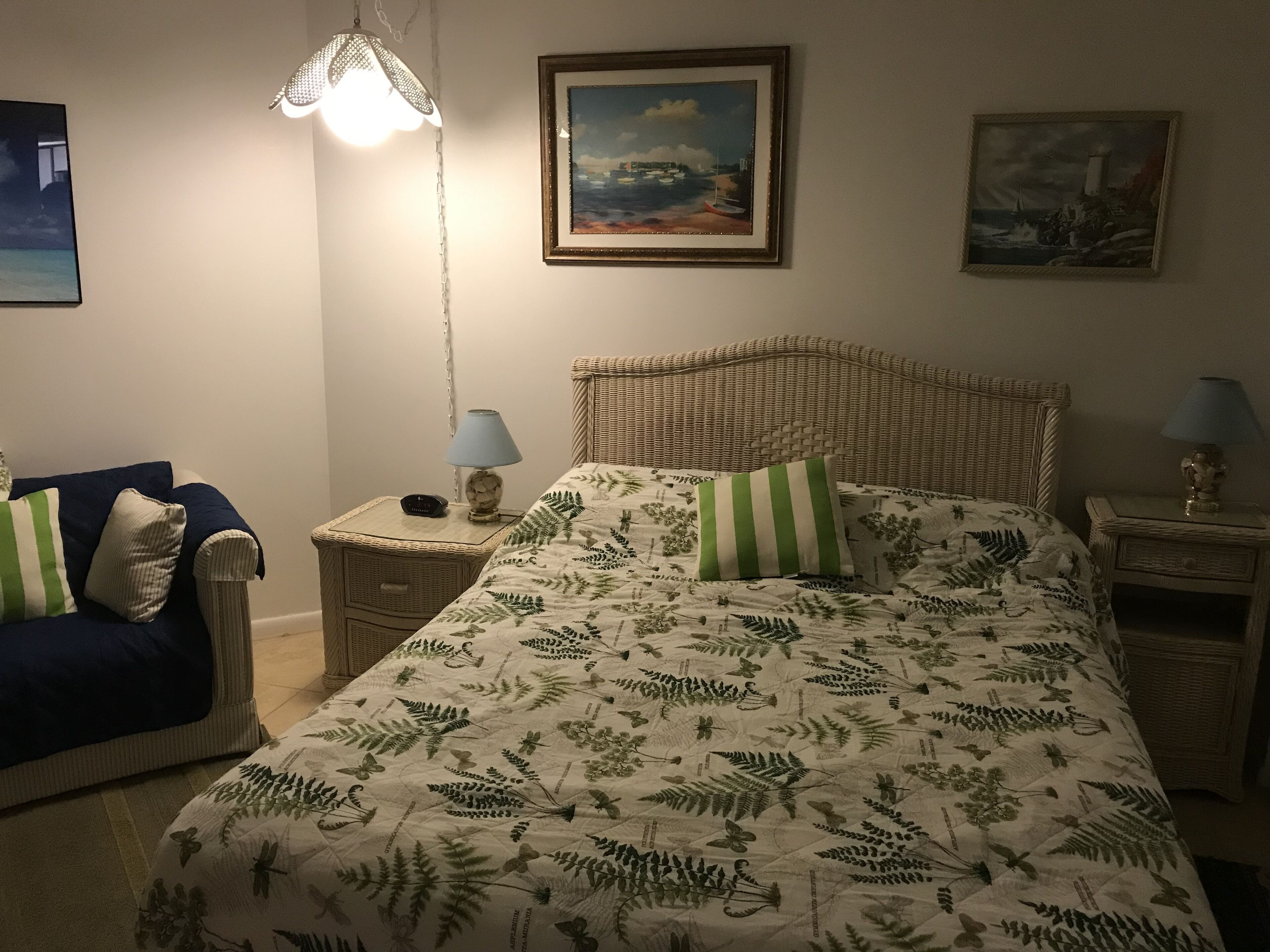 Ett sovrum med en säng, två sängbord, en stol och två lampor.