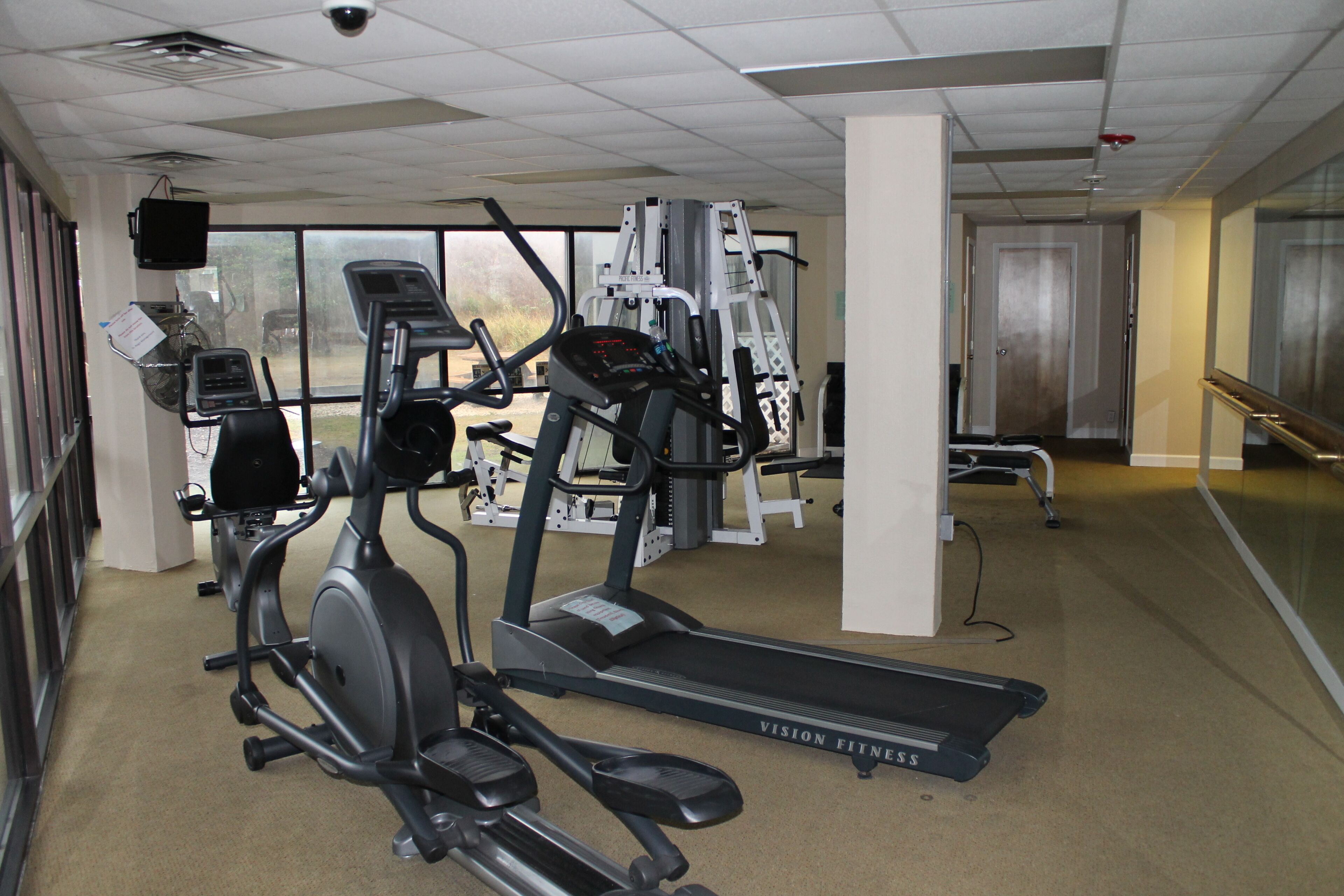 Ein Fitnessstudio mit Laufbändern, Crosstrainern und Gewichtsgeräten.