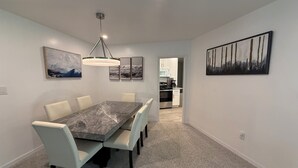 A modern dining room with a marble table and light-colored chairs, a chandelier, and artwork on the walls. - Sleeps 10 - Available Year Round -  Huge Private Home (Sanibel)