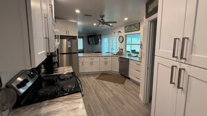 A modern kitchen with white cabinets, a stainless steel refrigerator, a black stove, and a ceiling fan. - Sleeps 10 - Available Year Round -  Huge Private Home (Sanibel)