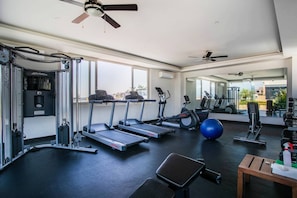 Une salle de sport équipée de tapis de course, de ballons d’exercice et d’appareils de musculation.