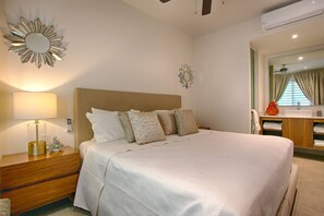 Un dormitorio ordenado con una cama grande, mesitas de noche, una lámpara y un espejo en la pared.