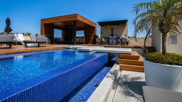 A pool area with a wooden deck, lounge chairs, and a covered seating area. - Modern Mexican 1BR | 2 Pool, Gym & Balcony (Puerto Vallarta)