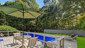 A wooden deck with a pool, outdoor furniture, and a green umbrella. - Perfect Family home, AC, Heated Pool, 3BR 2Bath (East Hampton)