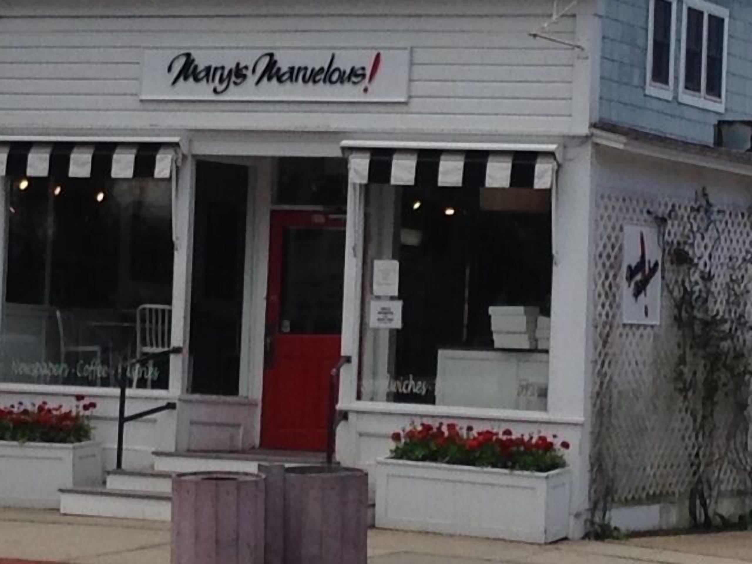 Une devanture de magasin avec une enseigne sur laquelle on peut lire « Mary’s Marvelous ! » et une porte rouge.
