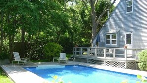 A backyard with a swimming pool, two lounge chairs, a wooden deck, and a house. - Perfect Family home, AC, Heated Pool, 3BR 2Bath (East Hampton)