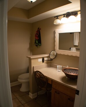 A bathroom with a toilet, a sink with a mirror, a towel rack, and a decorative plant. - Direct Oceanfront Luxury, Miles of Ocean View, King bed, Walk-in Shower. (Hilton Head Island)