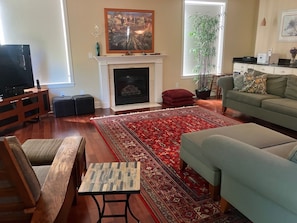 A living room with a fireplace, a television, a sofa, a coffee table, and a patterned rug.