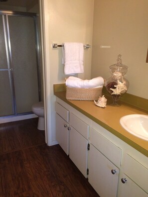 A bathroom with a shower, toilet, and a sink with a wicker basket and decorative items on the counter. - Lakefront Gated Brockway Springs Condo (Kings Beach)