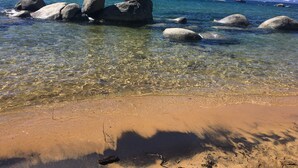 Una playa despejada con rocas grandes en el agua y una orilla arenosa.