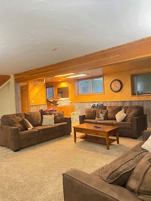 A cozy living room with two brown sofas, a wooden coffee table, and a fireplace.