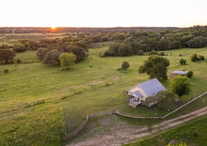 Propiedad rural con una casa grande, áreas cercadas y un paisaje circundante.